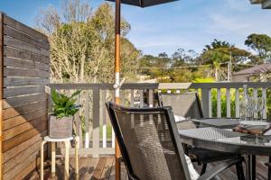 una mesa y sillas en una terraza con sombrilla en Amongst the Palms Inverloch, en Inverloch