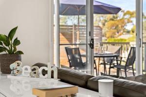 sala de estar con sofá de cuero y patio en Amongst the Palms Inverloch, en Inverloch 5 fotos más