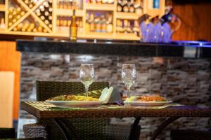 a table with two plates of food and wine glasses at Bwizi Resort and Gardens in Kanyigiri