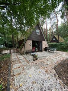 une maison avec un banc devant elle dans l'établissement Dennenrust A-frame huisje middenin het bos., à Lanaken