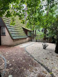 une maison avec une clôture à côté d'une cour dans l'établissement Dennenrust A-frame huisje middenin het bos., à Lanaken