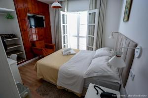 a bedroom with a bed with white sheets and a window at Siena Hotel in Campos do Jordão