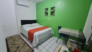 um quarto verde com uma cama e uma mesa em São Luís Hostel em São Luís