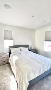 um quarto com uma grande cama branca e 2 janelas em NEW Luxurious 5BR/3BATHES Home, Spacious and Retreat location with Modern Amenities em Ontario