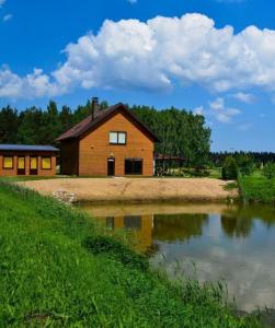 una cabaña de madera junto a un río con una casa en Pakavciems pirts en Riga