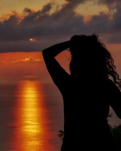 une femme debout en face de l'océan au coucher du soleil dans l'établissement Orbi city With sea view, à Batoumi