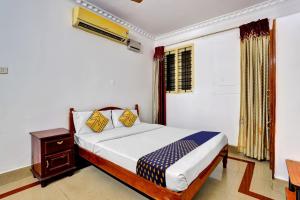 1 dormitorio con cama, mesa y ventana en OYO Majestic Inn, en Trivandrum