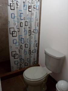 a bathroom with a toilet and a shower curtain at Hospedaje Kaihalulu in Punta Hermosa