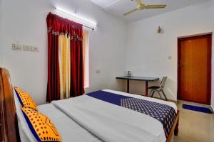 a bedroom with a bed and a table and a window at OYO Majestic Inn in Trivandrum