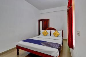 a bedroom with a bed with yellow and blue pillows at OYO Majestic Inn in Trivandrum