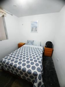 a bedroom with a bed with a black and white comforter at Hospedaje Kaihalulu in Punta Hermosa