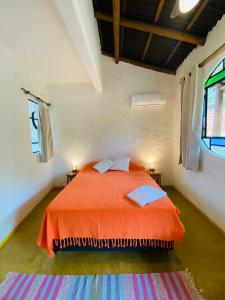 um quarto com uma cama com uma colcha laranja e 2 janelas em Hospedaria Pimenta Rosa - Serra Grande - BA em Serra Grande