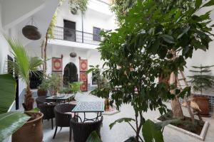 a courtyard with tables and plants in a building at Origin Hotels Riad Lhena in Marrakech