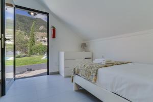 a white bedroom with a bed and a large window at Passion Villa in Machico +30 photos