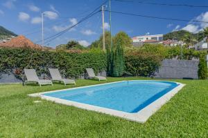 a swimming pool in the grass with two lounge chairs at Passion Villa in Machico