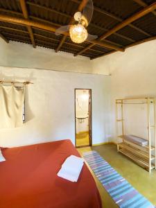 a bedroom with a red bed and a ceiling fan at Hospedaria Pimenta Rosa - Serra Grande - BA in Serra Grande