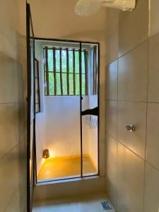 um chuveiro com uma porta de vidro na casa de banho em Hospedaria Pimenta Rosa - Serra Grande - BA em Serra Grande