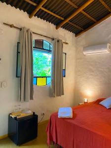 a bedroom with a red bed and a window at Hospedaria Pimenta Rosa - Serra Grande - BA in Serra Grande