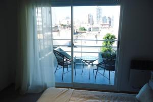 a room with a balcony with a table and chairs at Nicasio apart green flowers cercano Movistar Arena, Obras Palermo, Centro, River, Velez in Buenos Aires