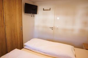 um pequeno quarto com uma cama e uma televisão em Ferienwohnung Alter Kuhstall em Neuenstein