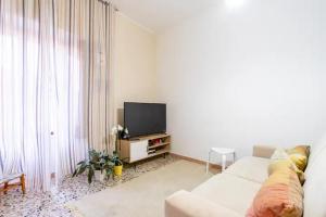 a living room with a white couch and a television at Casa castello in Rocca Imperiale