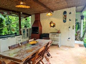 a kitchen with a wooden table and a dining room at Floresta Encantada in Ubatuba