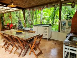 uma cozinha com uma mesa e cadeiras num pátio em Floresta Encantada em Ubatuba