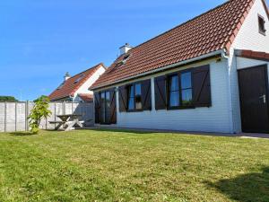 una casa blanca con una valla y un patio en Holiday home De Haan en De Haan