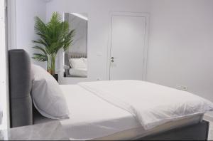 a white bedroom with a bed and a mirror at Suncity Tirana Luxury Apartments in Selitë e Vogël