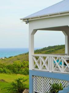 uma vista para o oceano a partir da varanda de uma casa em Pearl's Hilltop Cottage 