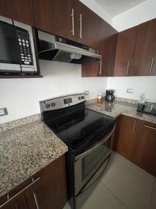 a kitchen with a black stove and a microwave at Los Próceres Apartamento Zona Exclusiva in Tegucigalpa