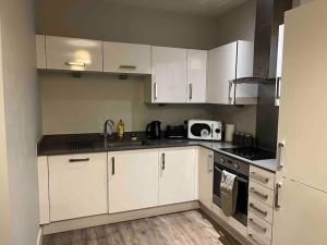 cocina con armarios blancos, fregadero y microondas en Apartment in Central Gillingham en Hoo