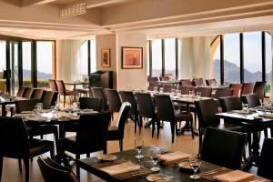 een eetkamer met tafels, stoelen en ramen bij Petra Marriott Hotel in Wadi Musa