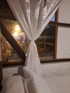 uma cama com uma cortina em frente a uma janela em Hotel Gabarra Lodge em San Vicente