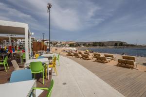 eine Terrasse mit Tischen und Stühlen und einem Strand in der Unterkunft Ligthbooking Arguineguin playa Lola in Arguineguín