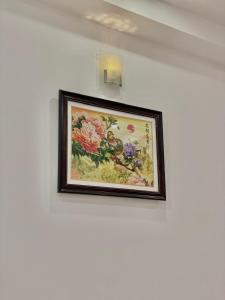 a framed picture of flowers on a white wall at Hà Tiên Hạnh Phúc Hotel in Hà Tiên