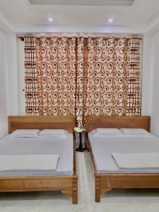 two beds sitting next to each other in a room at Hà Tiên Hạnh Phúc Hotel in Hà Tiên