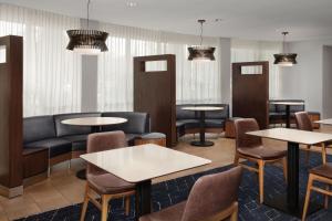 a waiting room with tables and chairs and a couch at Courtyard Jacksonville Flagler Center in Jacksonville