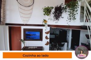 uma sala de estar com televisão e plantas na parede em Casa 5km Praia Coroa Vermelha 1 quarto no Térreo em Santa Cruz Cabrália