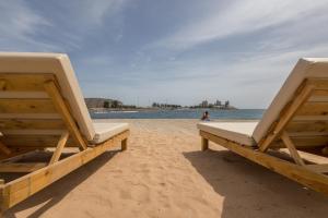 zwei Stühle am Strand mit dem Ozean im Hintergrund in der Unterkunft Ligthbooking Arguineguin playa Lola in Arguineguín