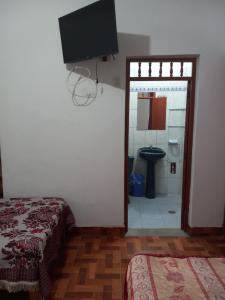 a bedroom with a bathroom with a toilet and a television at FLOWERs HOSTEL in Nazca