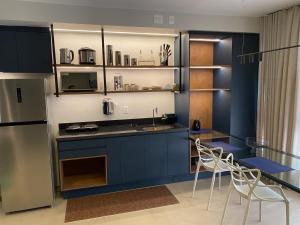 a kitchen with blue cabinets and a table and chairs at Studio Books Id Vida Urbana in Goiânia