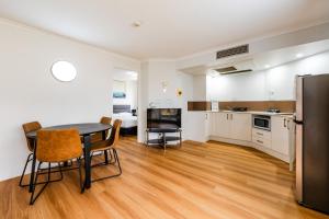 een keuken en een woonkamer met een tafel en stoelen bij Abbey On Roma Hotel & Apartments in Brisbane