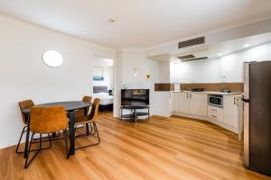 a kitchen and living room with a table and chairs at Abbey On Roma Hotel & Apartments in Brisbane