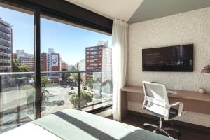 a bedroom with a bed and a window and a chair at Diseño en Punta Carretas con garaje opcional in Montevideo