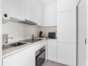 eine weiße Küche mit weißen Schränken und einem Waschbecken in der Unterkunft Isis 1 bedroom on floor 5 in Blankenberge