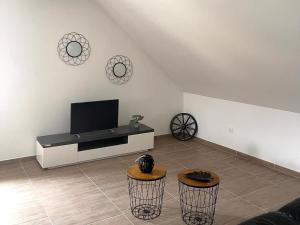 ein Wohnzimmer mit einem Flachbild-TV und 2 Hockern in der Unterkunft Apartment for 4 people, in the heart of Alsace in Châtenois