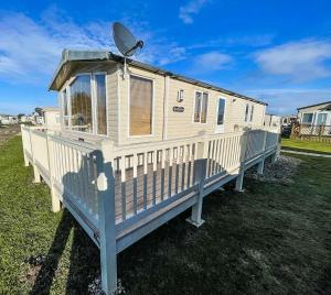 a mobile home with a satellite on a deck at Lovely Caravan With Spacious Decking At North Denes In Suffolk, Ref 40134nd in Lowestoft