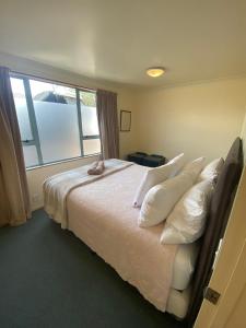 a bedroom with a bed with white pillows and a window at Tairua Dream in Tairua