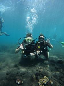 twee mensen in het water met een duikapparaat bij Melasti Mountain Villas, Amed, Room 3 Agung Guesthouse in Amed